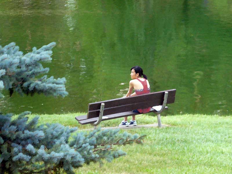 Young woman takes a rest on a park bench. In MooScience.